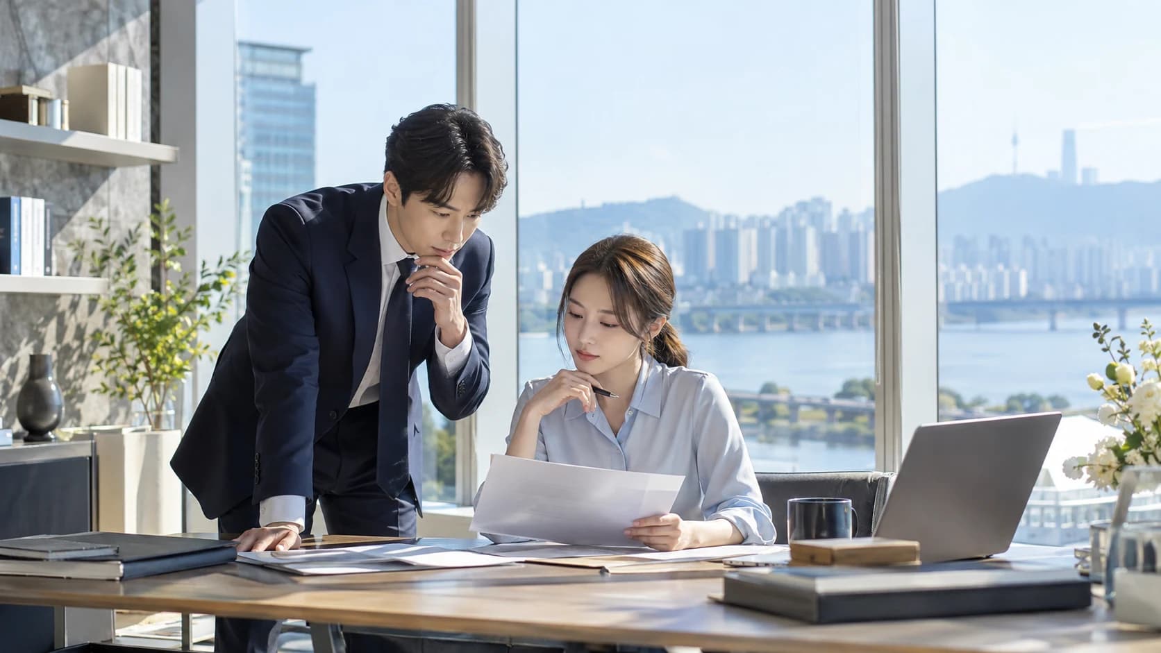 Two people reviewing documents and a laptop together in a bright office